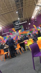 People sat down on colourful chairs, inside Kirkgate Market in Leeds.