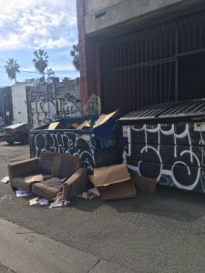 Rubbish bins covered in graffiti, which are overflowing.