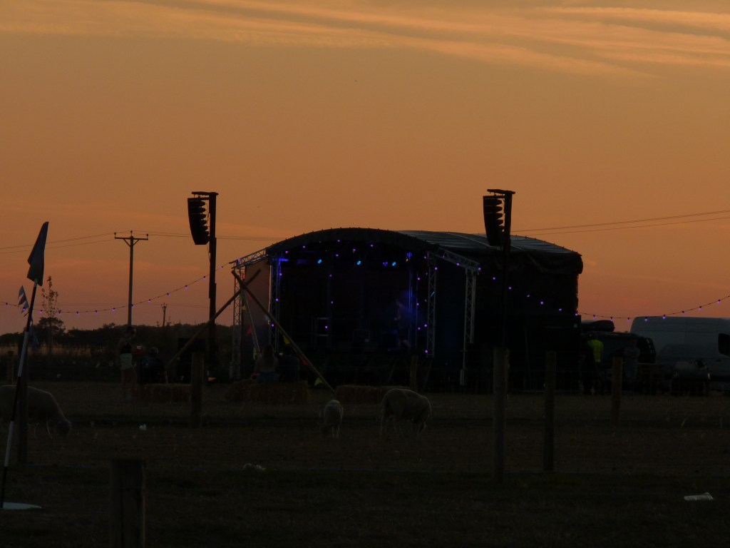 One of the stages at Rand Farm Festival, against the back-drop of an orange sunset.